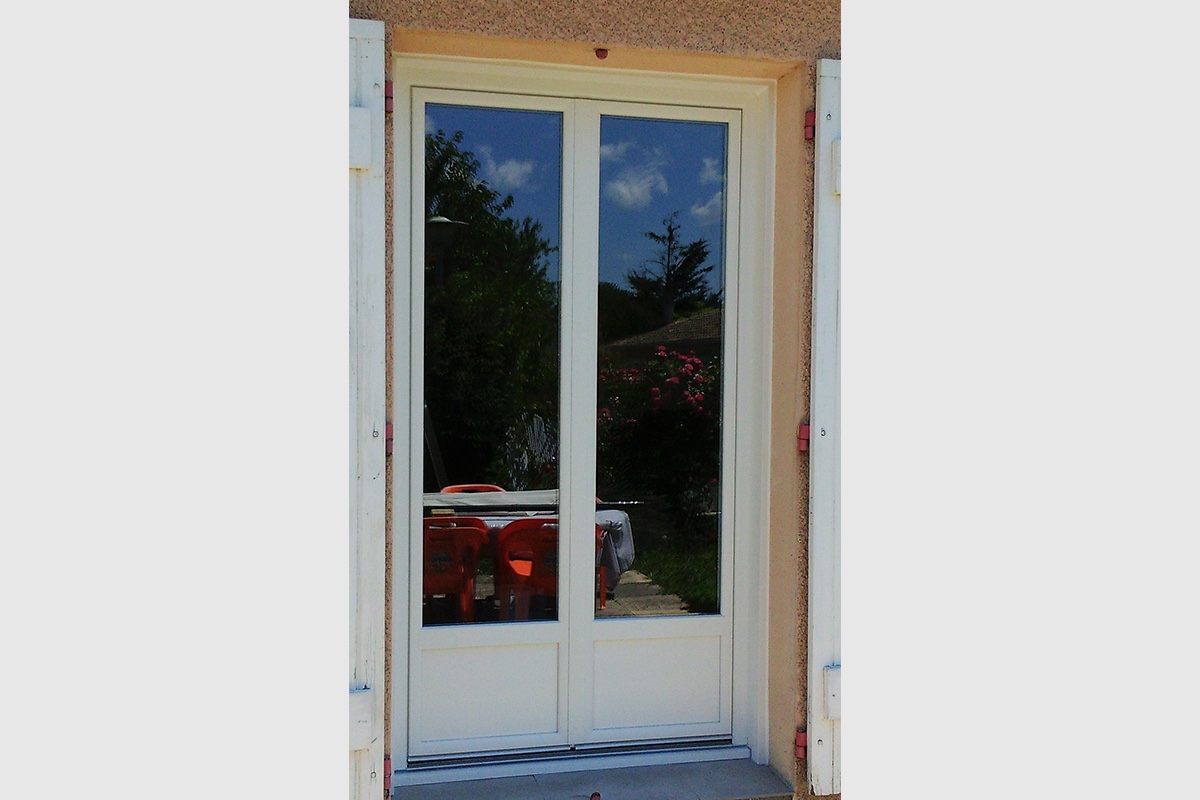 Porte-fenêtre en pvc blanc. Soubassement plein sur le bas de la porte.